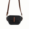 Saffiano flap crossbody bag in black - product front view on beige background with brown strap
