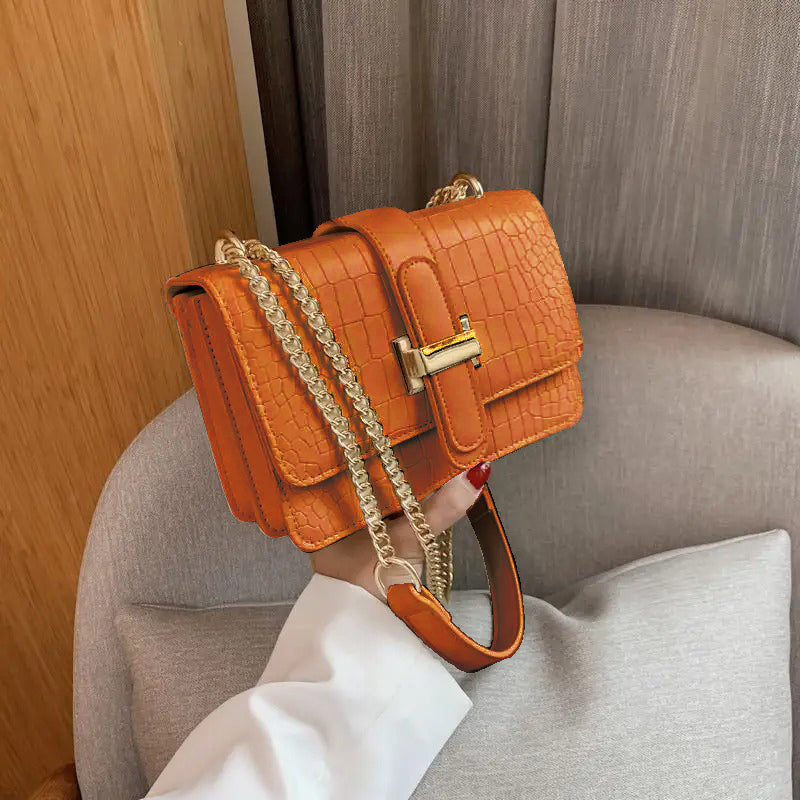 Croc T-lock chain crossbody bag in orange - model holding bag with gold chain strap