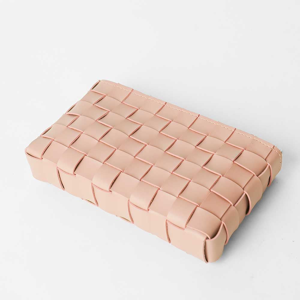 Woven leather crossbody clutch in blush pink - flat lay top-down view on white surface