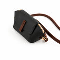 Saffiano flap crossbody bag in black - close-up of gold carabiner clip and brown strap attachment