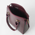 Maroon structured top handle handbag - side profile view on white background showing pink piping trim