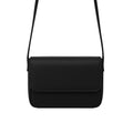 Magnetic crossbody bag in black - lifestyle front view with white flowers and gold rings