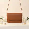 Magnetic crossbody bag in brown/tan - lifestyle front view with white flowers