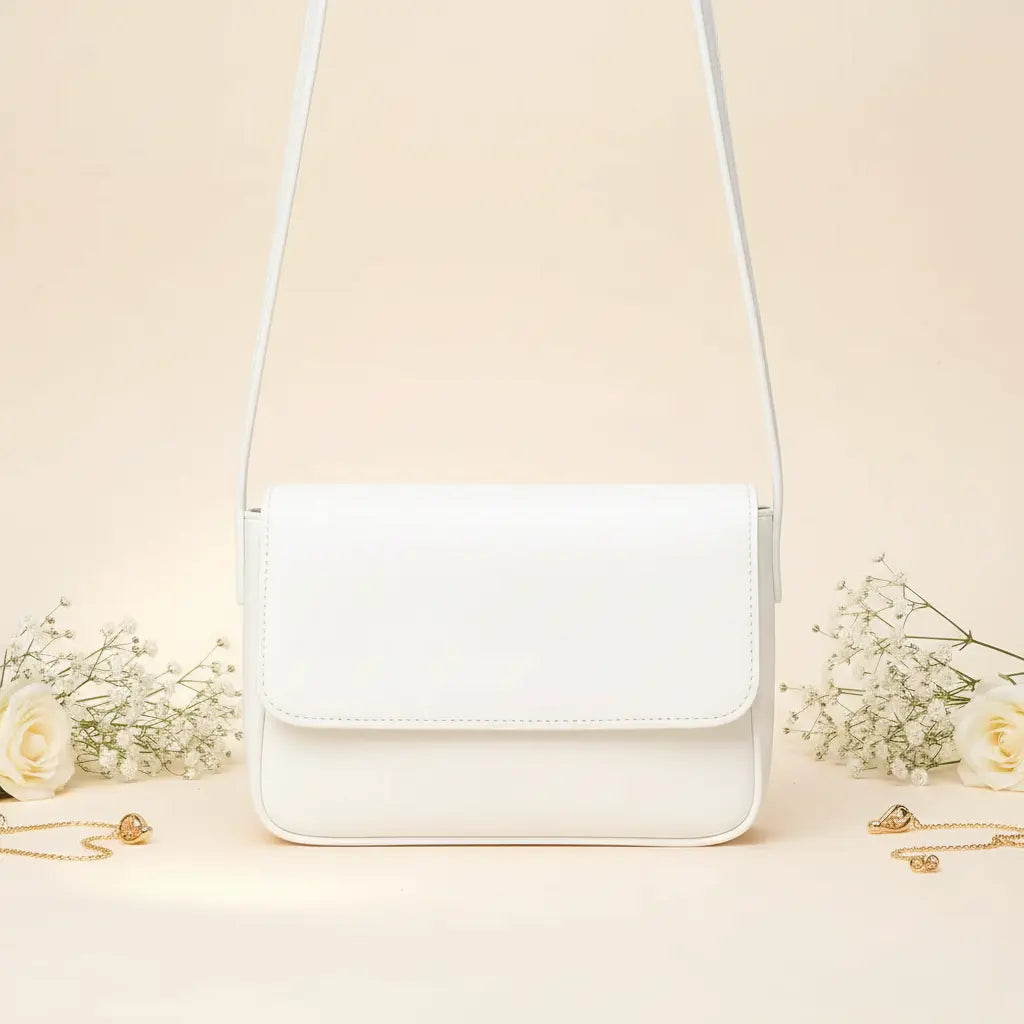 Magnetic crossbody bag in white - lifestyle front view with white flowers and gold chain accessories