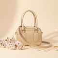 Noor classic handbag in skin/beige trim - side angle view with pink flowers and gold chain