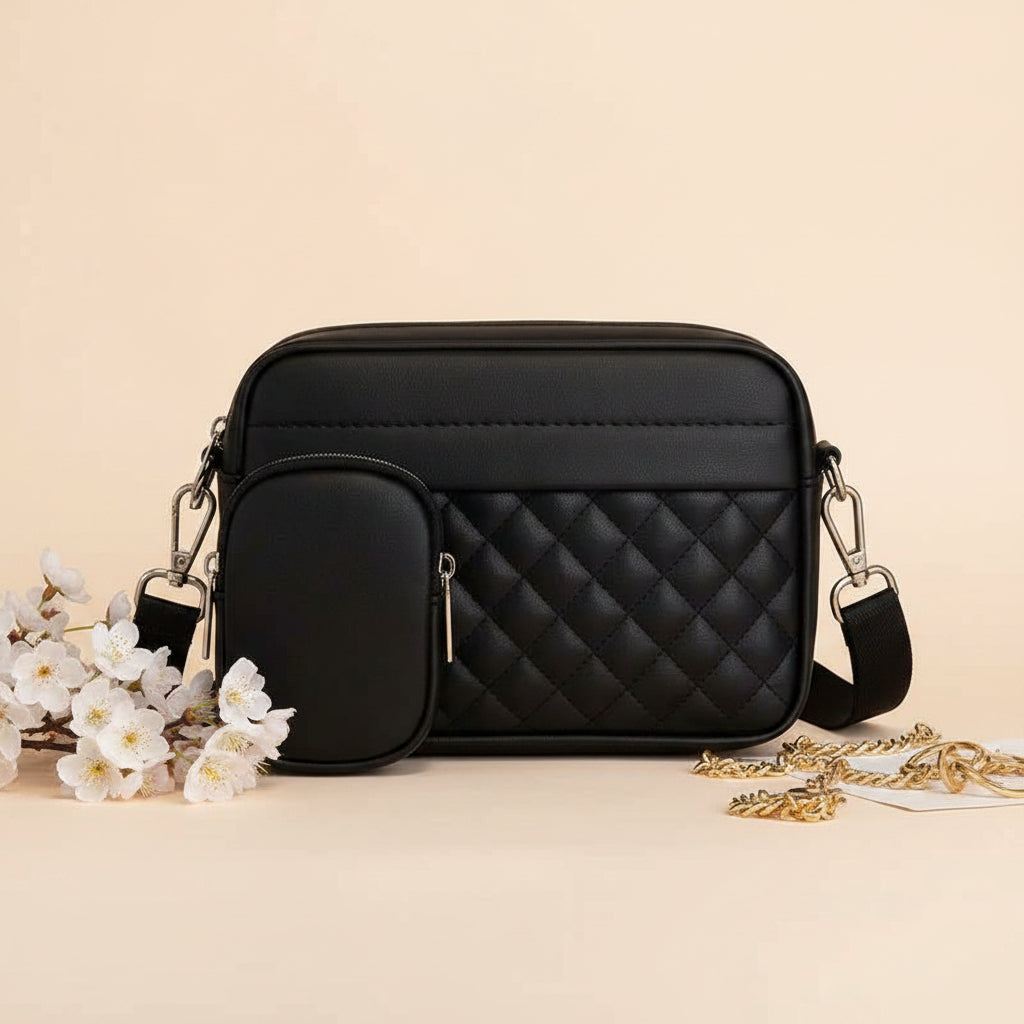 Quilted crossbody bag with coin pocket in black - lifestyle front view with white flowers and gold chain